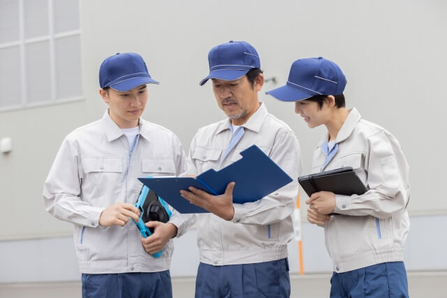 工場の前で書類を確認する作業員